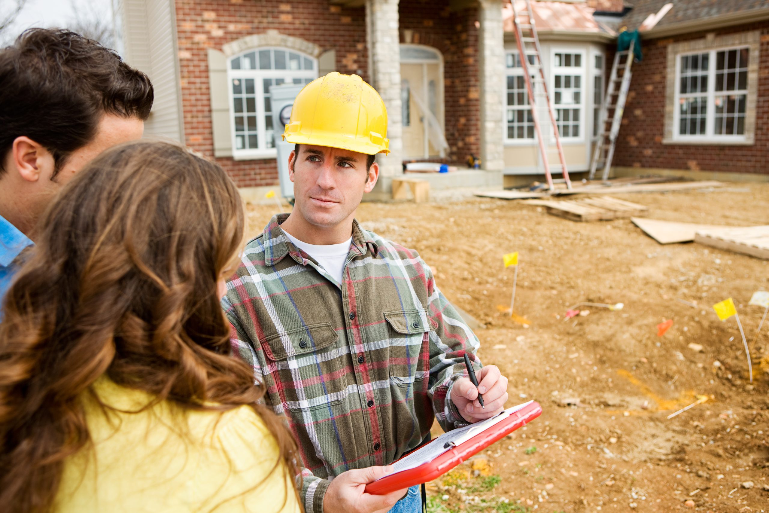 image shows contractor in hard hat discussing estimate for new roof with married couple